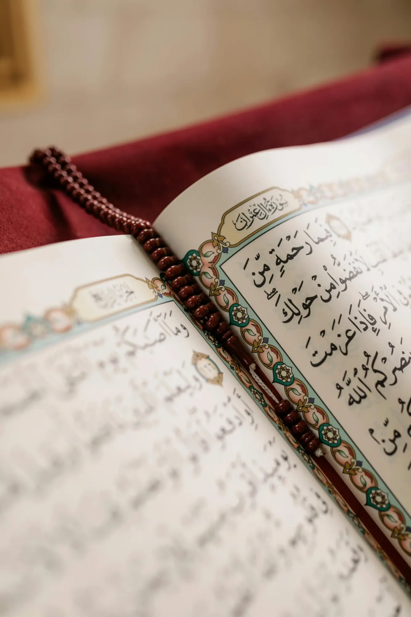 A close-up of an open Quran page with prayer beads resting on it