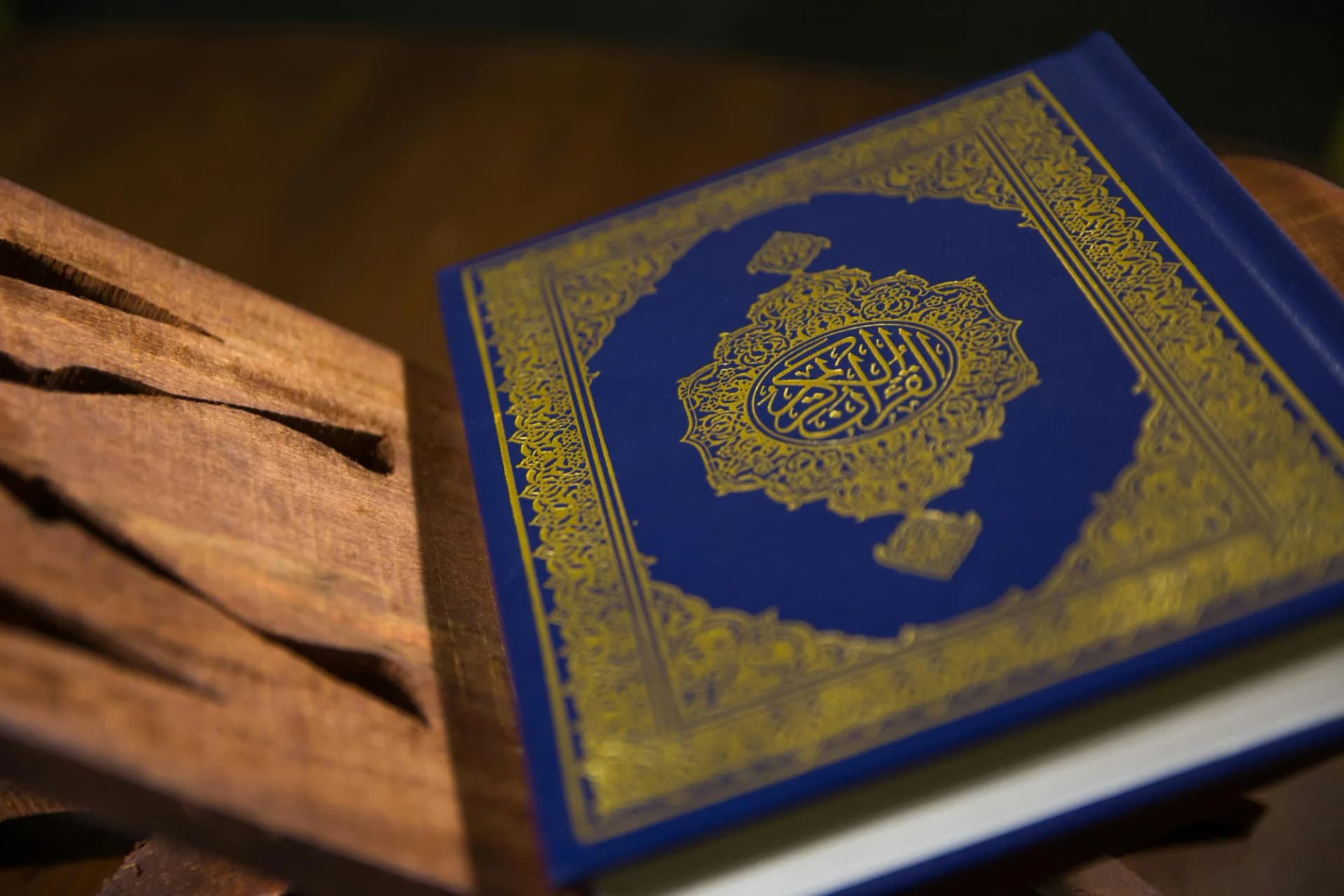 An ornate blue and gold Quran resting on a wooden stand