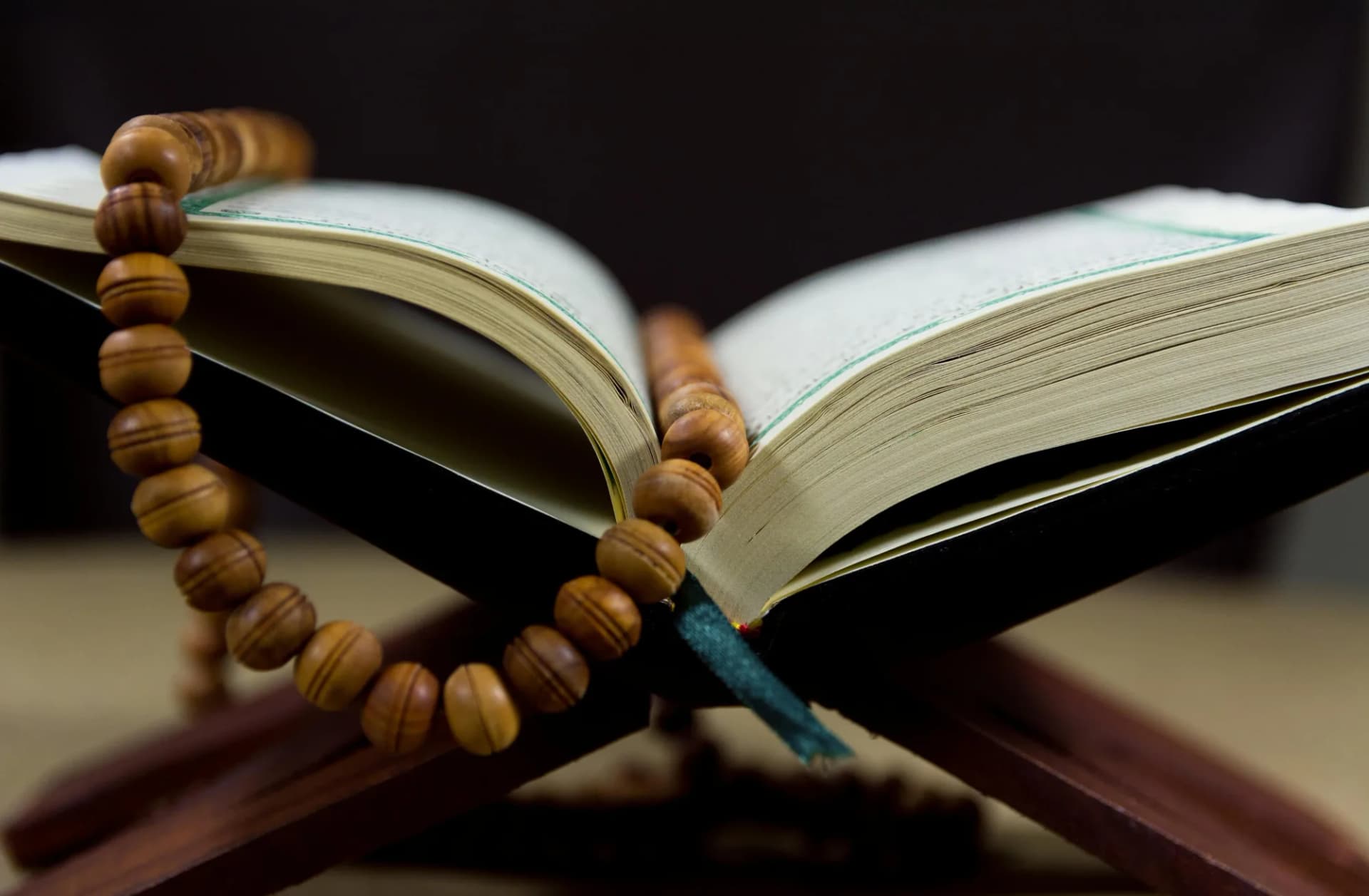 A Quran open on a dark surface with soft light across the pages